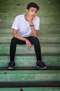 Portrait of young man sitting on wall