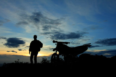 Silhouette man standing on field against sky during sunset