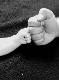 Cropped image of father and son giving fist bump on blanket