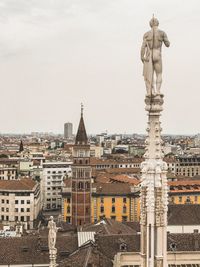 Statue in city against sky