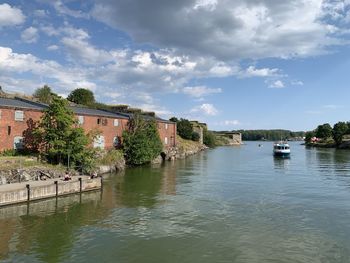 Scenic view of river by buildings against sky