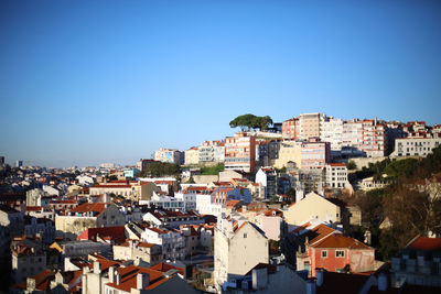 Buildings in city against clear blue sky