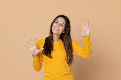 Portrait of smiling young woman against gray background