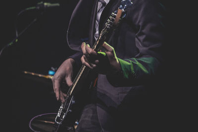 Midsection of man playing electric guitar on stage