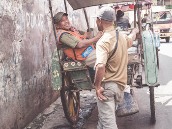 Rear view of men standing on street in city