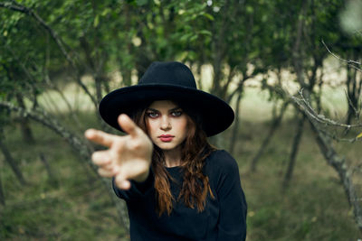 Portrait of young woman wearing hat standing in forest