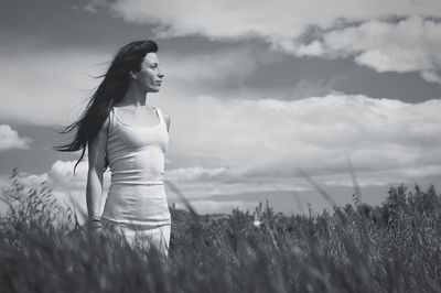 Woman with umbrella on field against sky