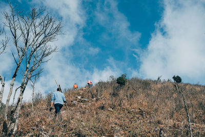 Rear view of hiking mans on field against sky