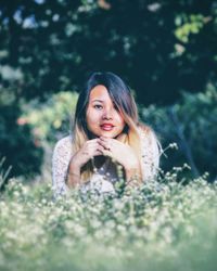 Portrait of smiling young woman against trees