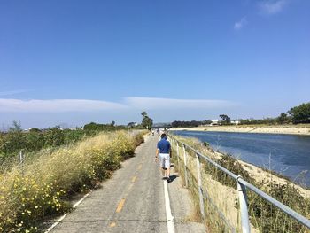 Rear view of woman walking on road against sky