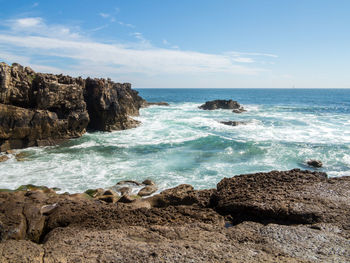 Scenic view of rocks on beach against sky