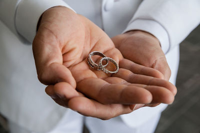 Midsection of man holding wedding rings