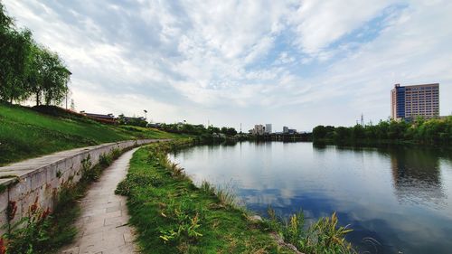 Scenic view of river by buildings against sky