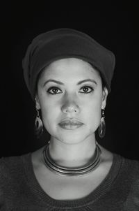 Close-up portrait of a smiling young woman over black background