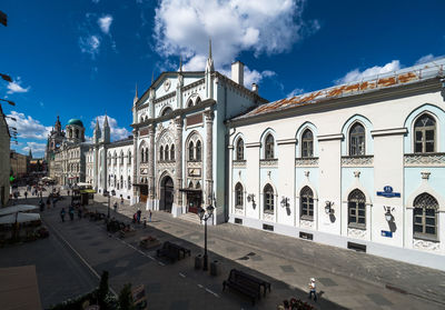 Panoramic view of people in front of building against blue sky