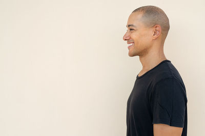 Side view of young man standing against wall