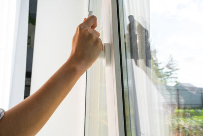 Cropped hand of person against window