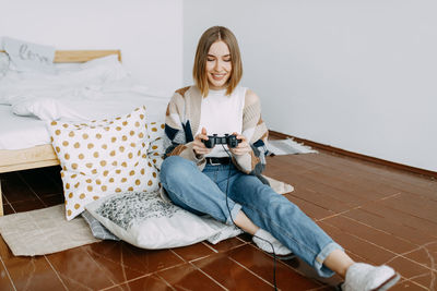 Young woman sitting on bed at home