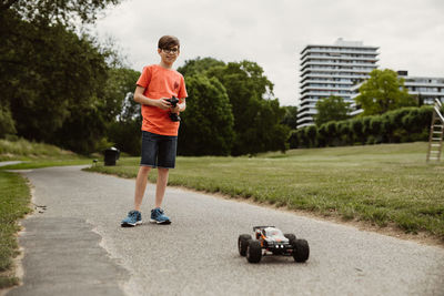 Teen boy with electric remote control car toy play outdoor on sidewalk and have fun while enjoy 