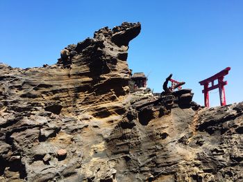 Low angle view of rock formations against clear blue sky