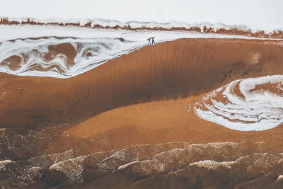Aerial view of friends lying at beach during winter