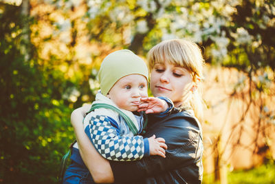 Side view of mother holding son while standing at park