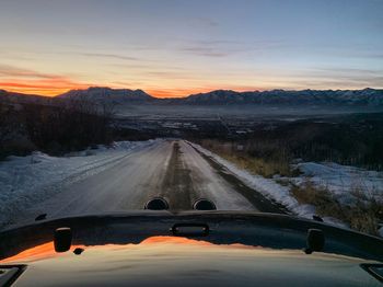 Road against sky during sunset seen through car windshield