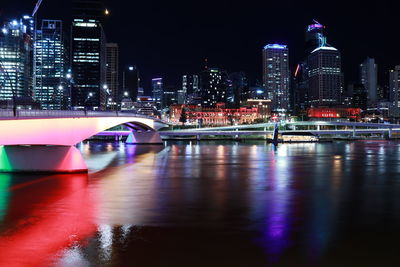 Illuminated buildings by river at night