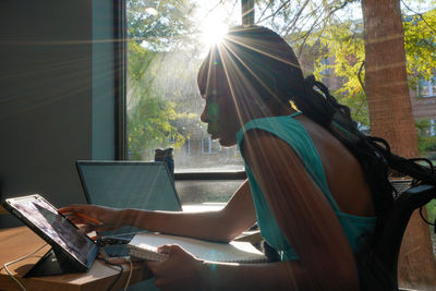 Rear view of woman using laptop at home