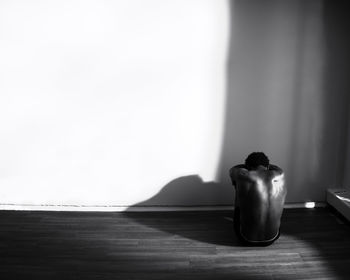 Man sitting sad and alone in a corner of an empty apartment