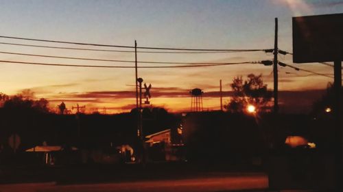 Power lines against sky at sunset