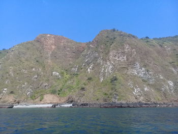 Scenic view of sea and mountains against clear blue sky