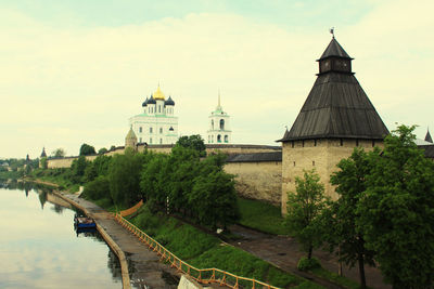 Bridge over river by buildings against sky