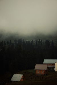 Houses by trees and buildings against sky