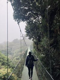 Rear view of man walking on footbridge