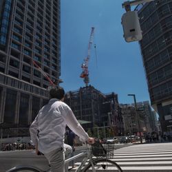 Rear view of man bicycling on road against sky