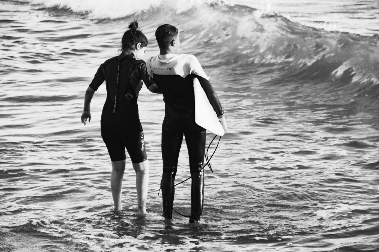 REAR VIEW OF WOMEN STANDING ON SHORE