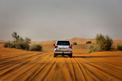 View of car in desert against sky