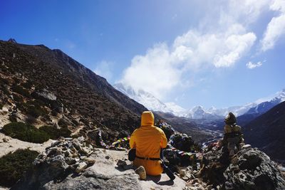 Rear view of people looking at mountain against sky
