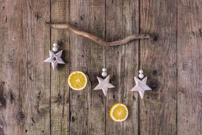 Sliced oranges with christmas decorations hanging from wooden wall