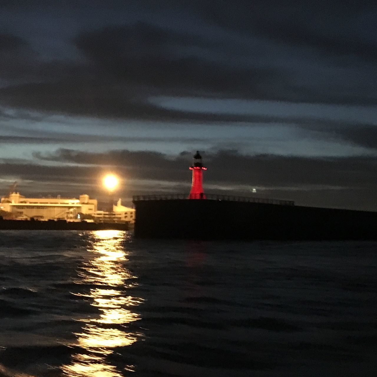 LIGHTHOUSE AMIDST SEA AGAINST SKY AT SUNSET