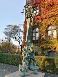 Sculpture by building against sky during autumn