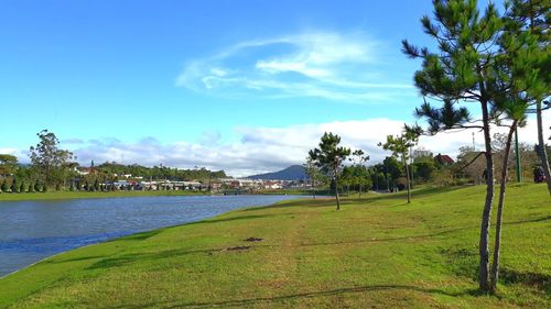 Scenic view of field by river against sky