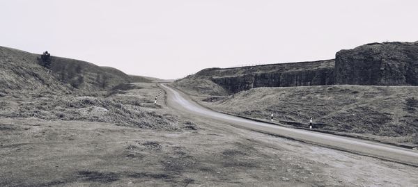 Road leading towards mountains against clear sky