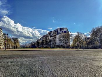 Road by buildings against sky in city