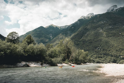 Scenic view of river by tree mountains against sky