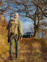 Rear view of man standing by bare tree