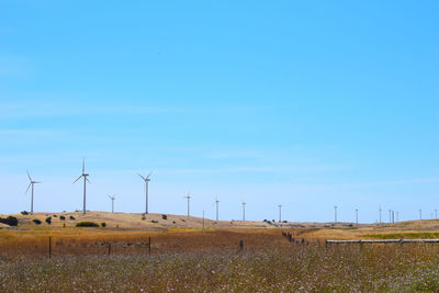 Wind turbines on field against sky