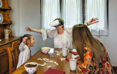 Grandmother with daughter and granddaughter wearing virtual reality simulator at home