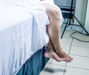 Low section of woman sitting on bed